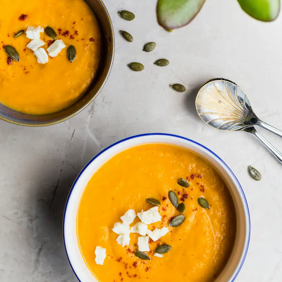 Bowl of orange squash soup topped with seeds
