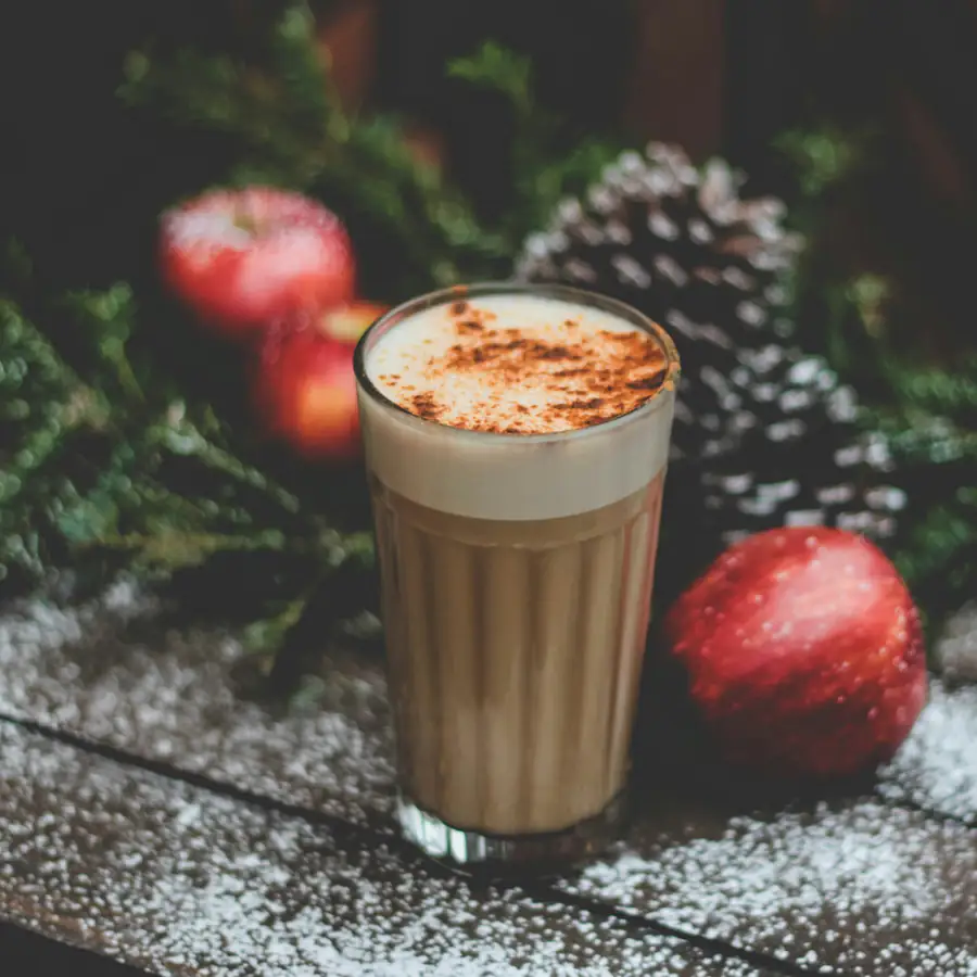 Glass of spiced chai latte beside red apples