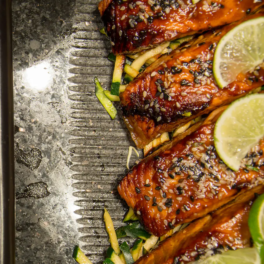 Glazed salmon fillets with sesame seeds and spring onion on a tray