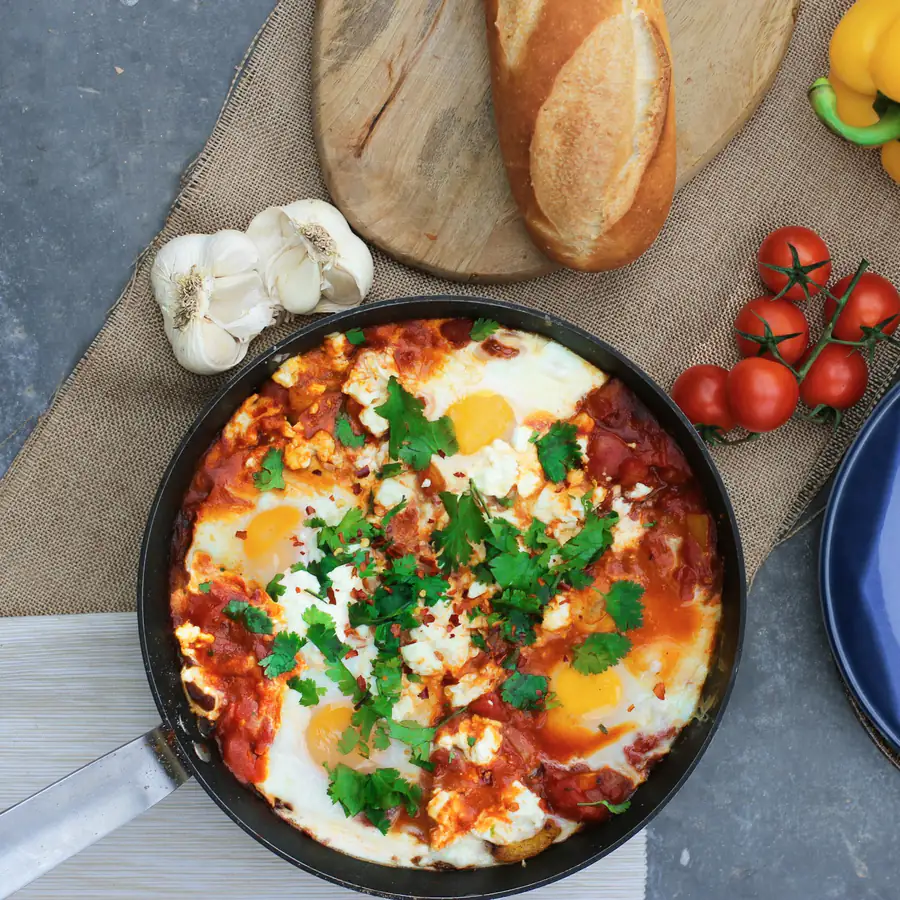 Pan of shakshuka with eggs and herbs