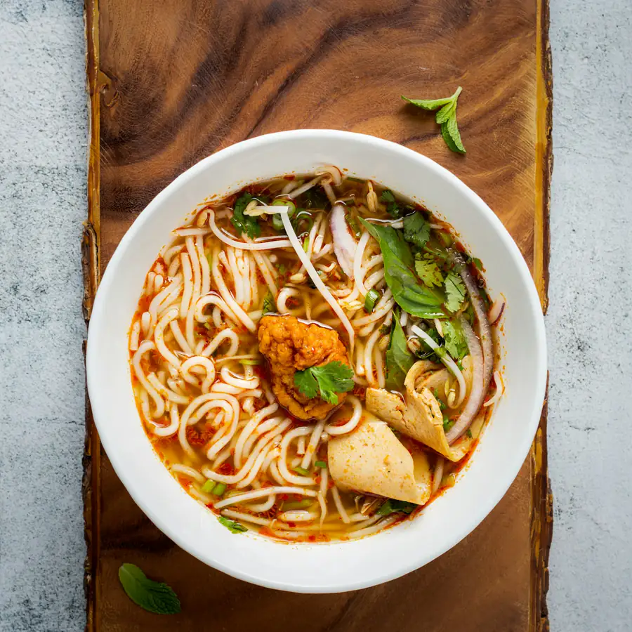 Bowl of noodle soup with chicken and herbs