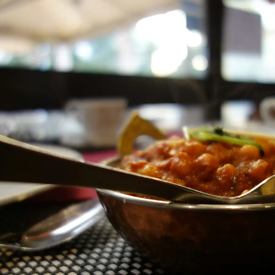Metal bowl of orange curry with a spoon