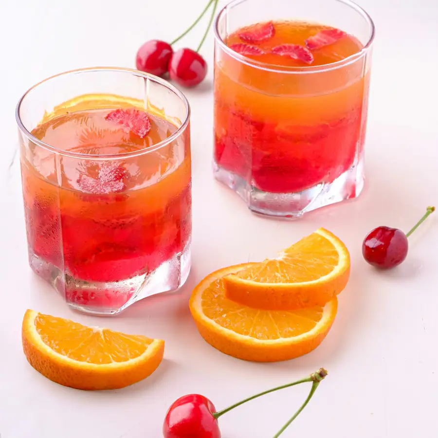 Glasses of red cherry drink with fresh cherries