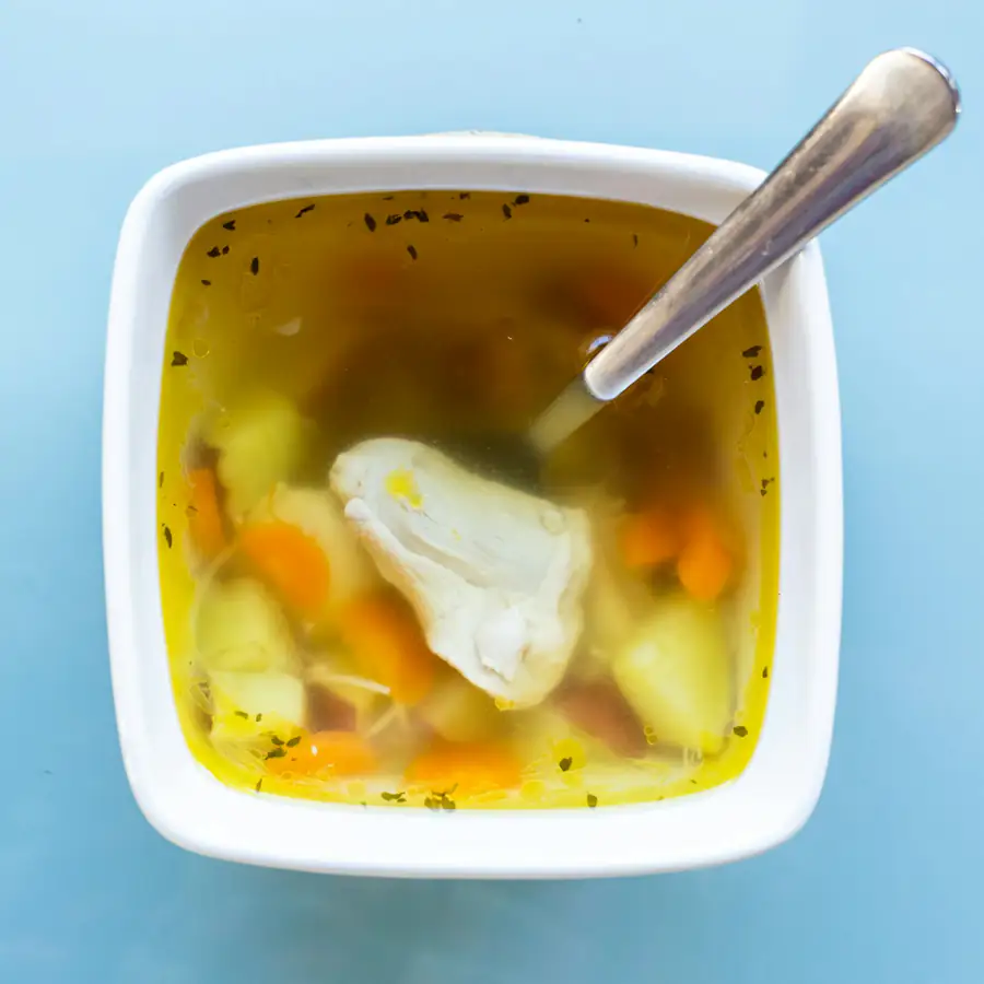 Bowl of chicken and vegetable soup with carrots
