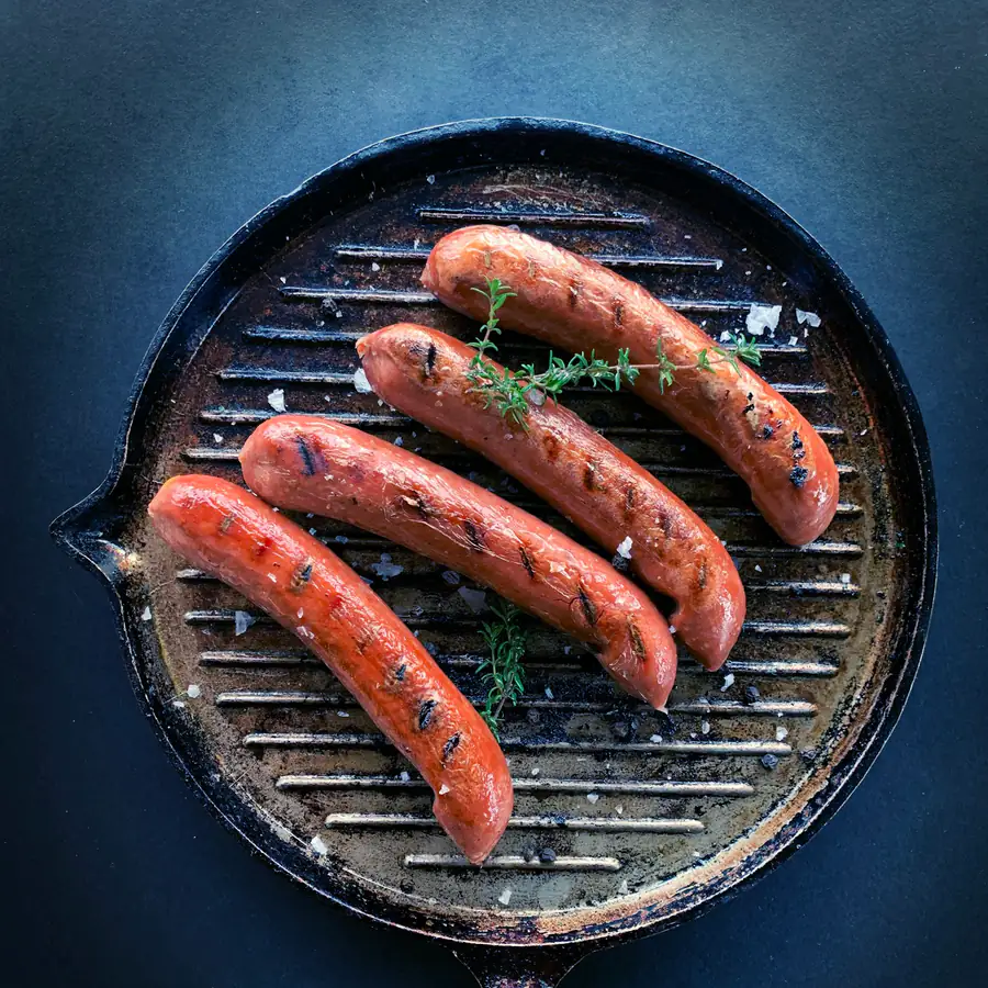 Sausages cooking on a round grill pan