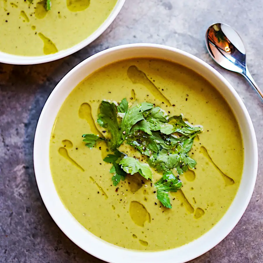 Bowls of green pea soup with herbs