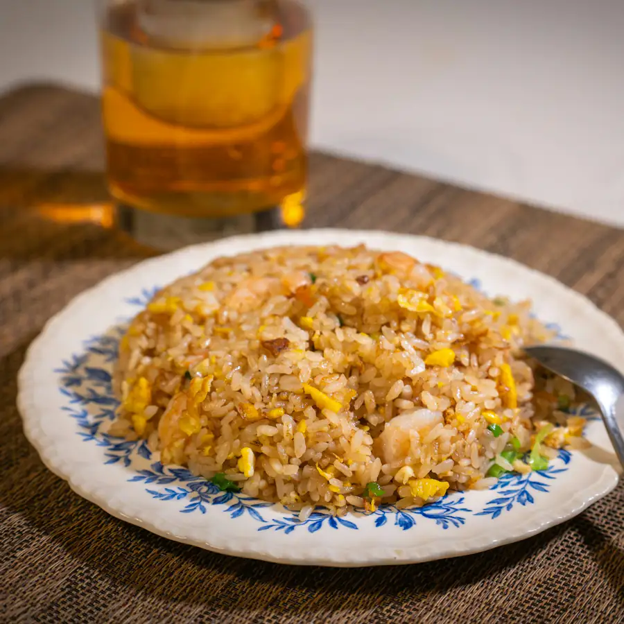 Plate of egg fried rice beside a glass of beer
