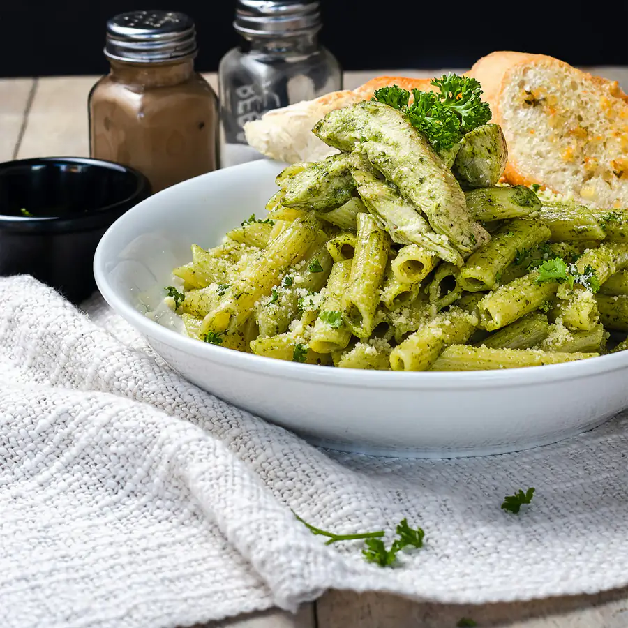 A bowl of pesto chicken pasta with fresh basil