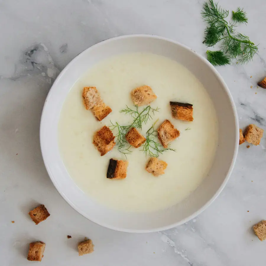 Bowl of creamy pale leek and potato soup with croutons