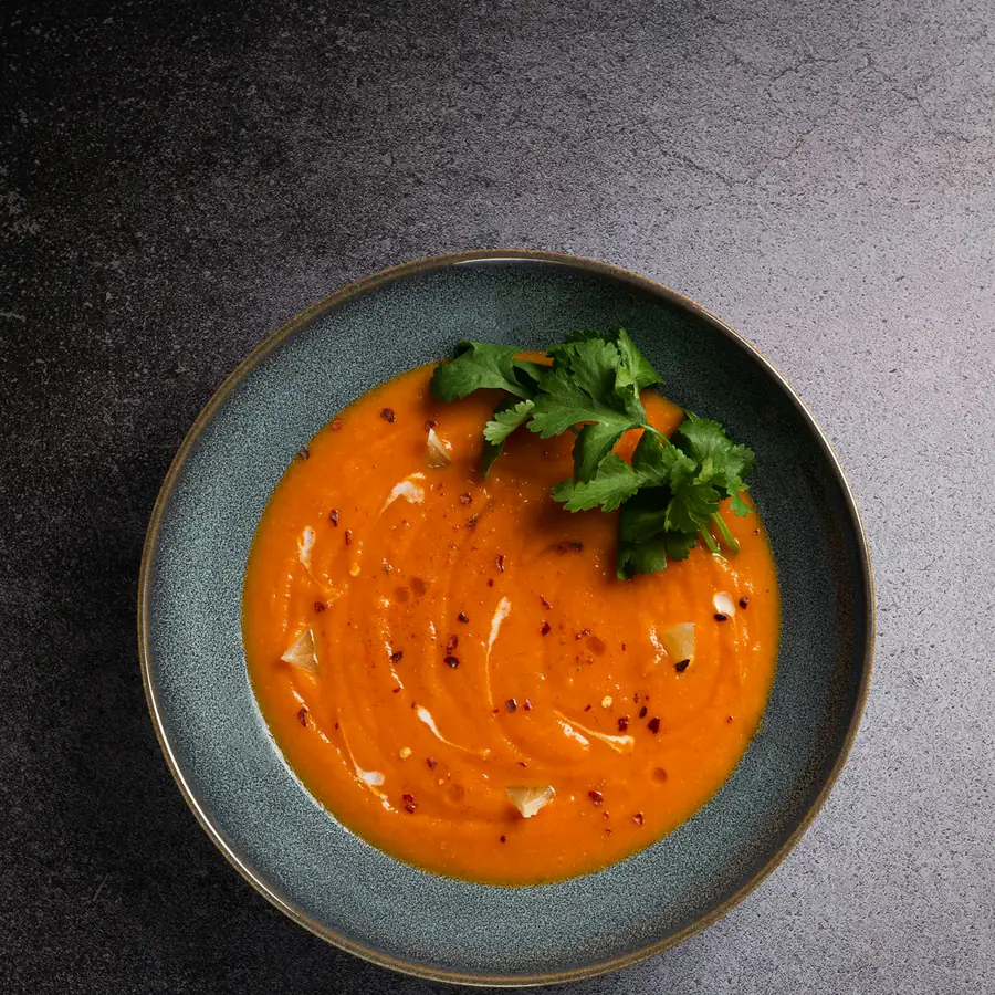 Bowl of smooth tomato soup topped with herbs