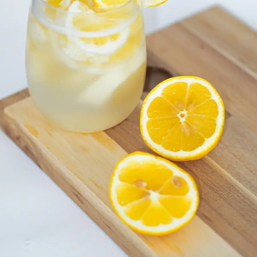 Glass of cloudy lemonade with lemon slices on a wooden board