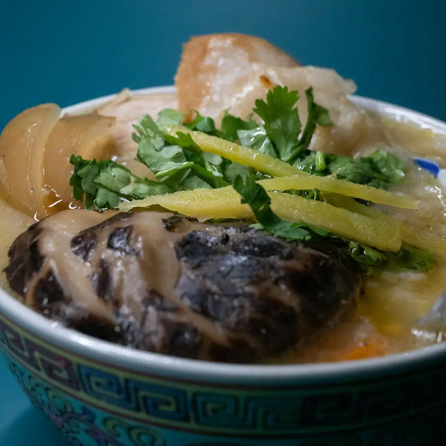 Bowl of rice congee topped with ginger and herbs