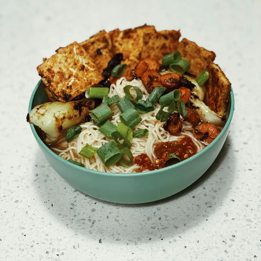 Noodle bowl topped with tofu and greens
