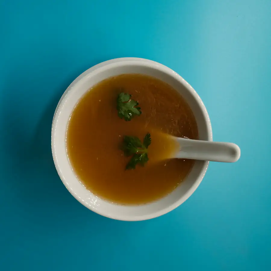 Bowl of clear golden broth with herbs