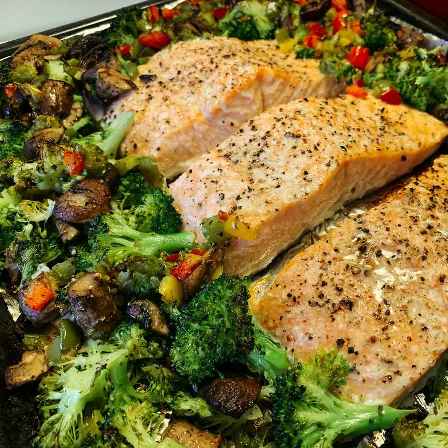 Salmon fillets baked in a tray with broccoli, mushrooms and red peppers