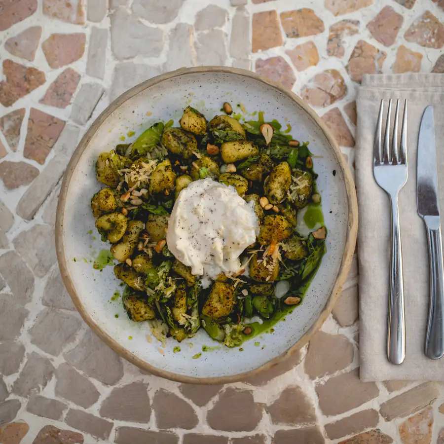 Plate of gnocchi with green pesto and grated cheese
