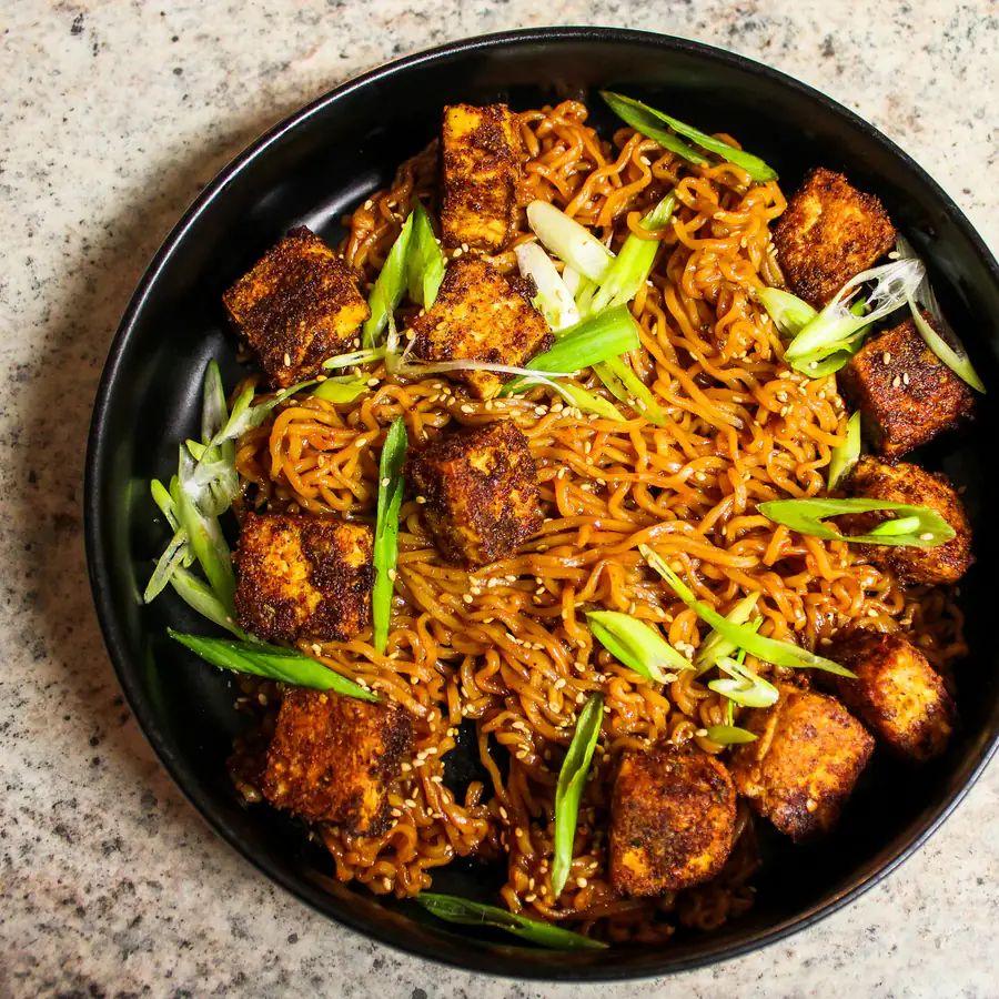 Bowl of noodles with crispy tofu and spring onion