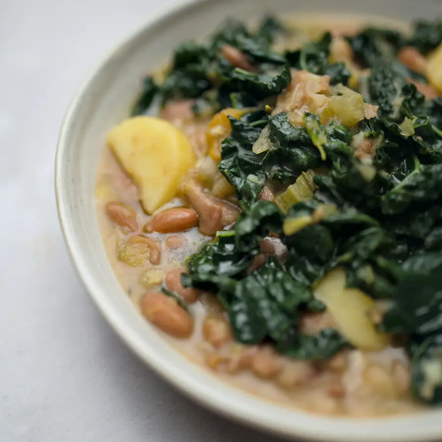 Bowl of white beans with greens and squash