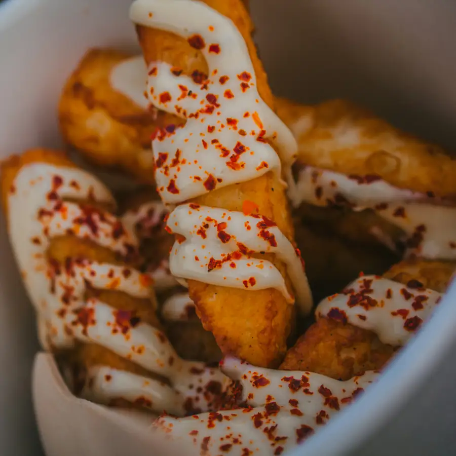 Golden halloumi fries in a bowl with a white drizzle and chilli flakes