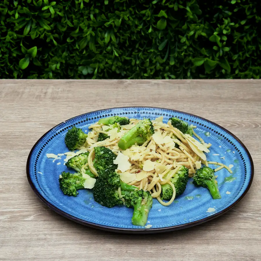 Blue plate of spaghetti with broccoli and grated cheese