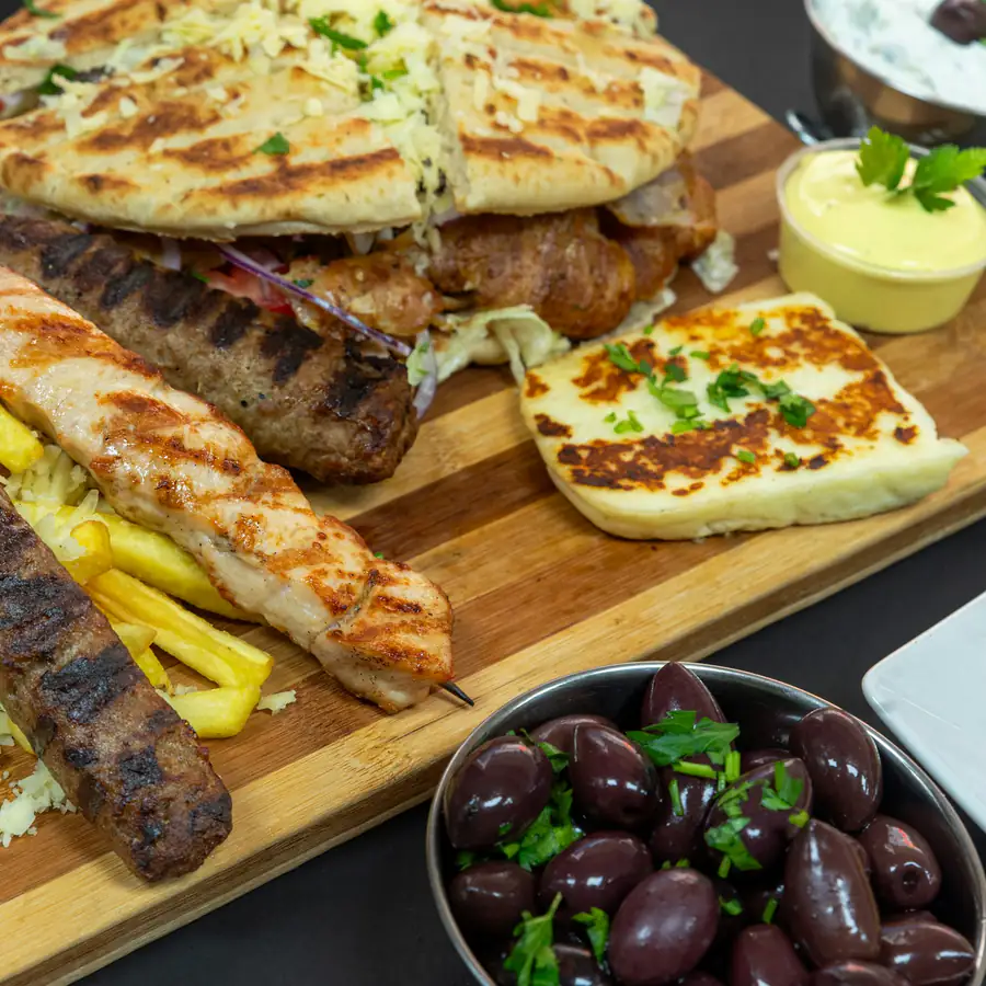 Grilled meat with flatbread, a bowl of tzatziki and olives