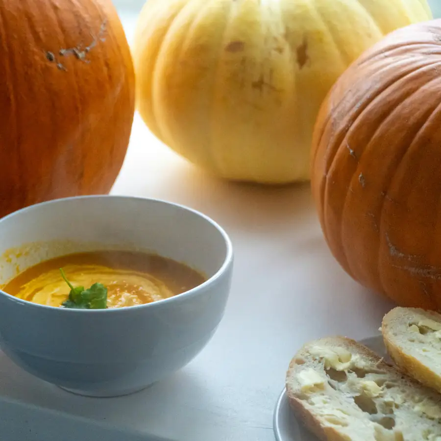 Bowl of orange squash soup in front of pumpkins