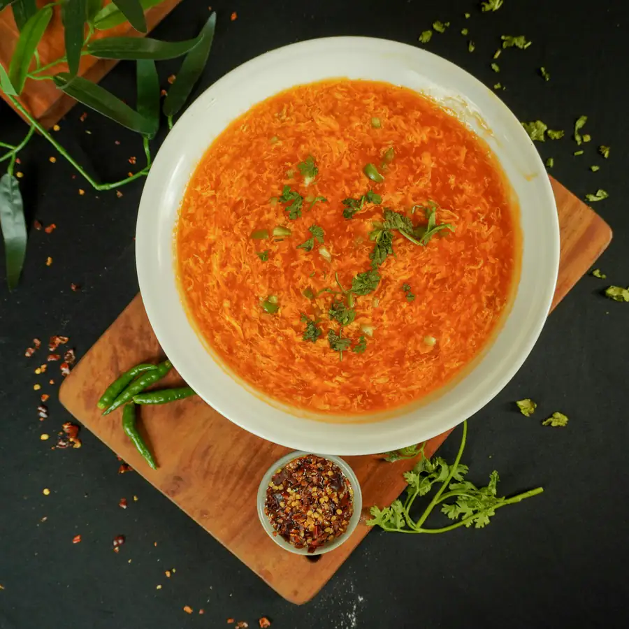 Bowl of orange red soup garnished with herbs